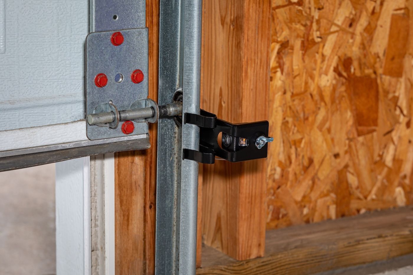 Garage door latch and track hardware secured to a wooden frame.