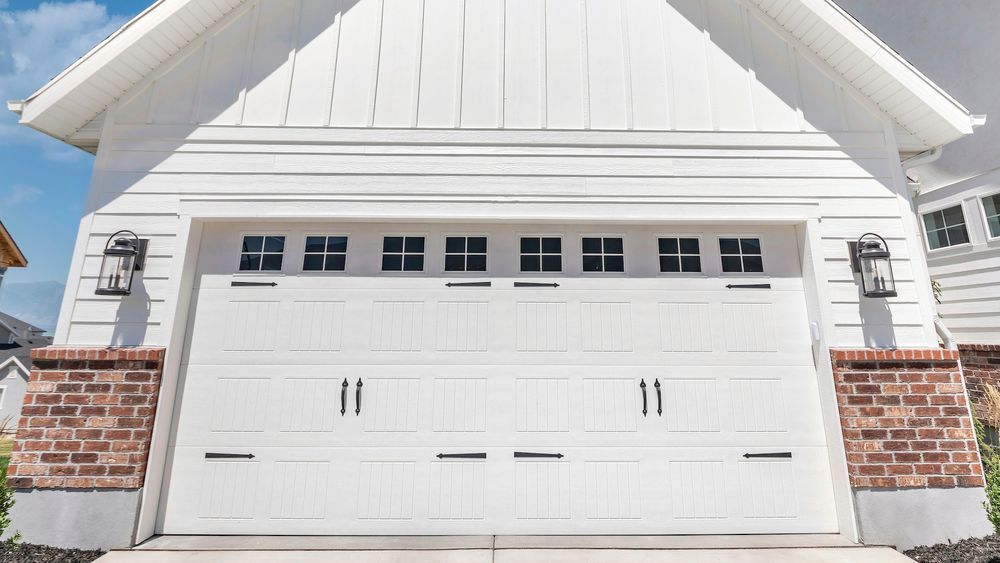 White garage door with windows, black hardware, and brick accents.