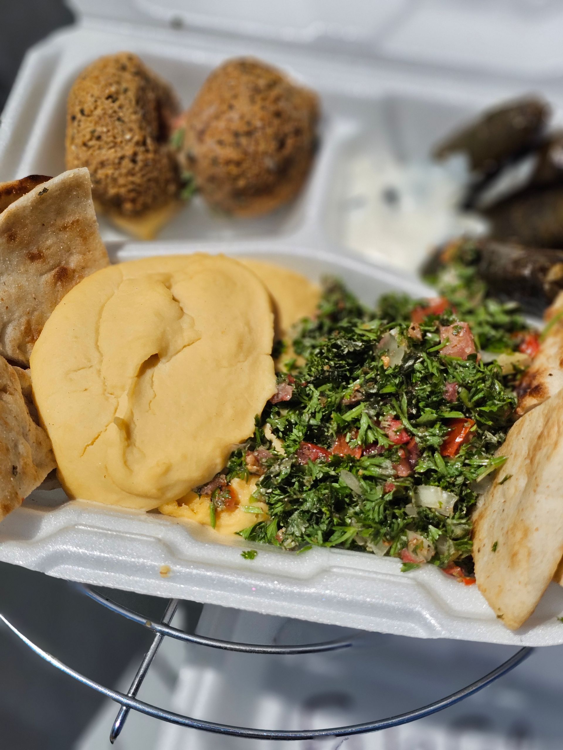 A plate of stuffed grape leaves with lemon slices on a table.