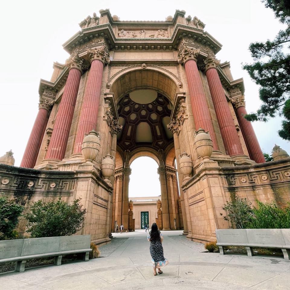 A woman is standing in front of a large building.