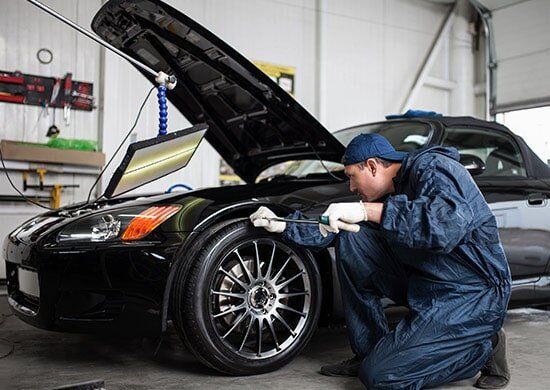 Mechanic Repairing Dent On Black Car — Paintless Dent Removal Gosford in West Gosford, NSW