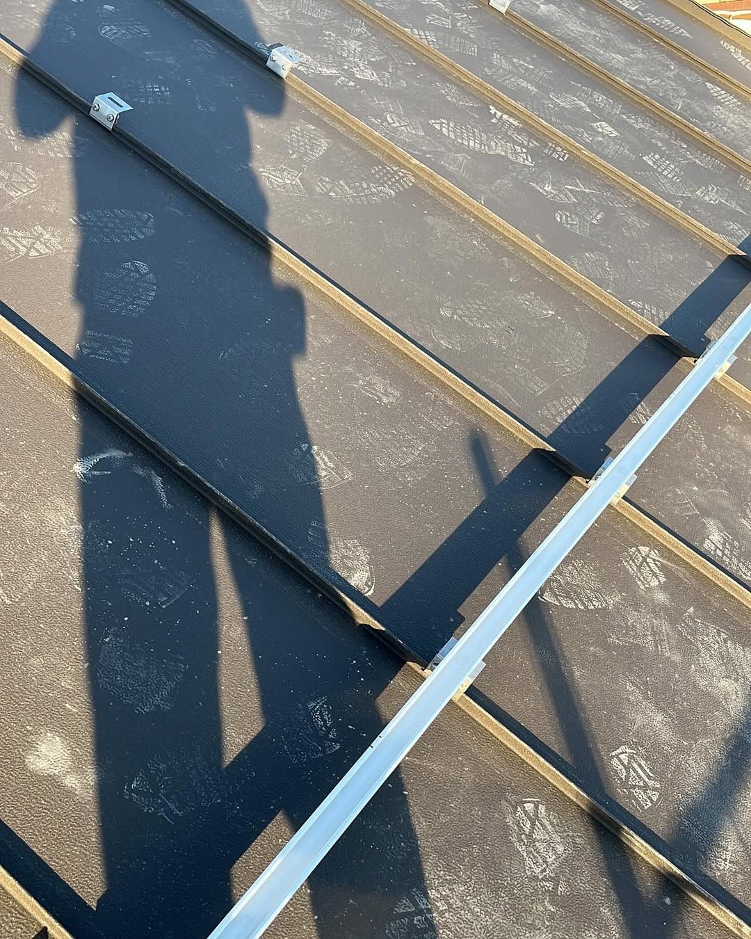 L'ombra di una persona proiettata su un tetto ricoperto di binari e staffe di montaggio per pannelli solari.