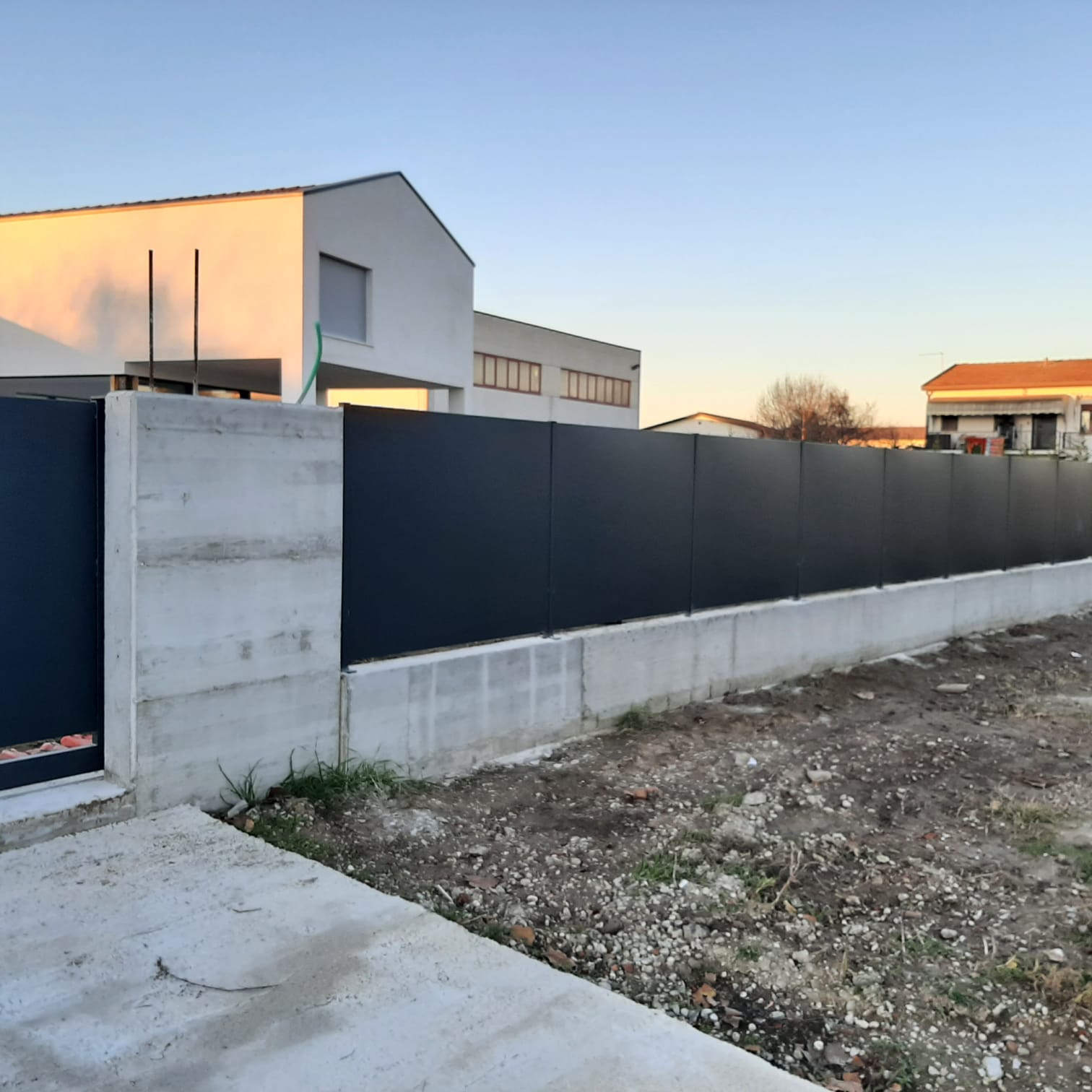 Recinzione nera su base di cemento di fronte a un moderno edificio bianco.