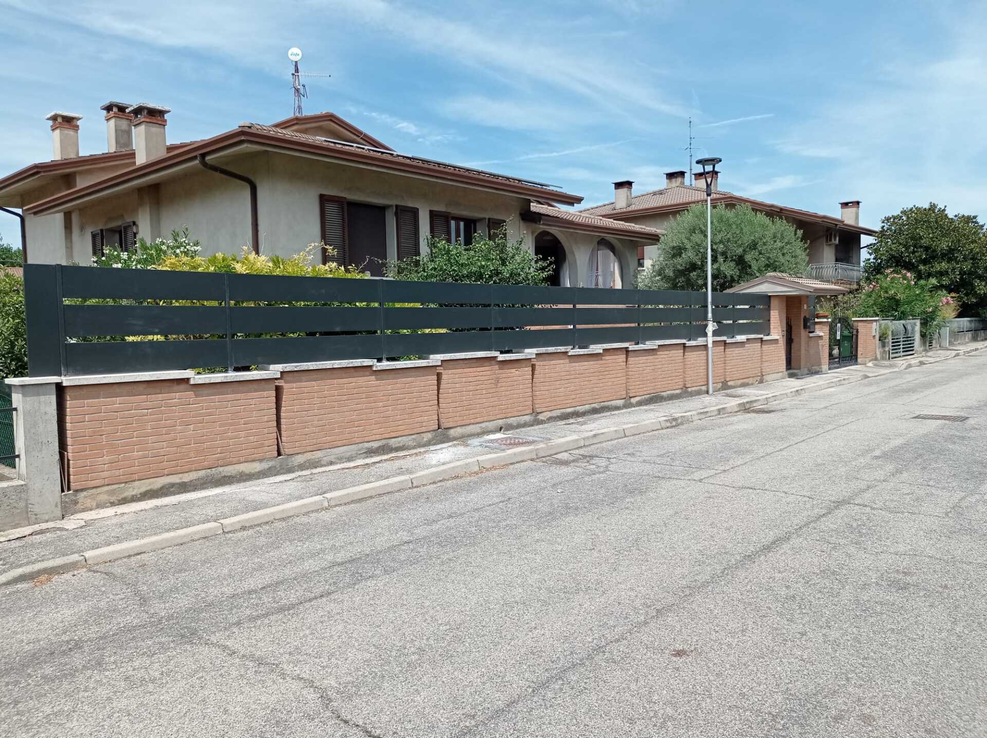 Case con recinzione scura lungo una strada.