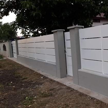 Recinzione bianca con listelli orizzontali e base in cemento grigio; ambiente esterno.