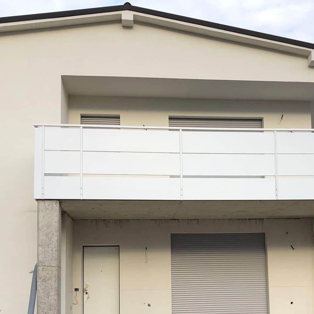 Esterno di un edificio moderno con balcone e porta del garage chiusa.