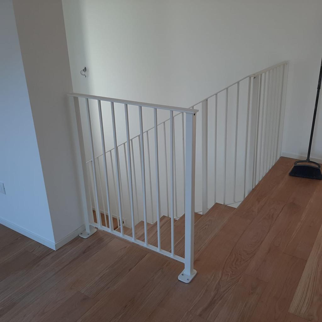 Scala bianca con ringhiera coordinata, pavimento in legno.