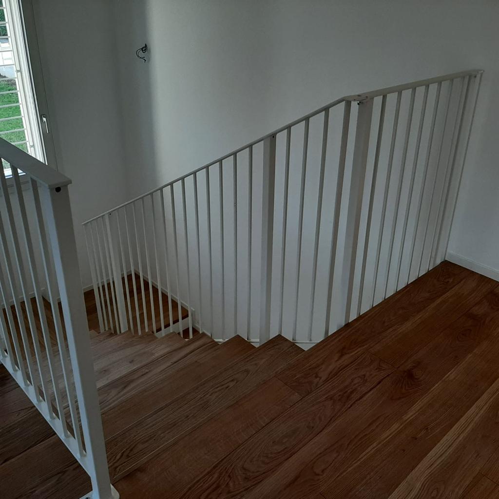 Scala in legno con ringhiere in metallo bianco.