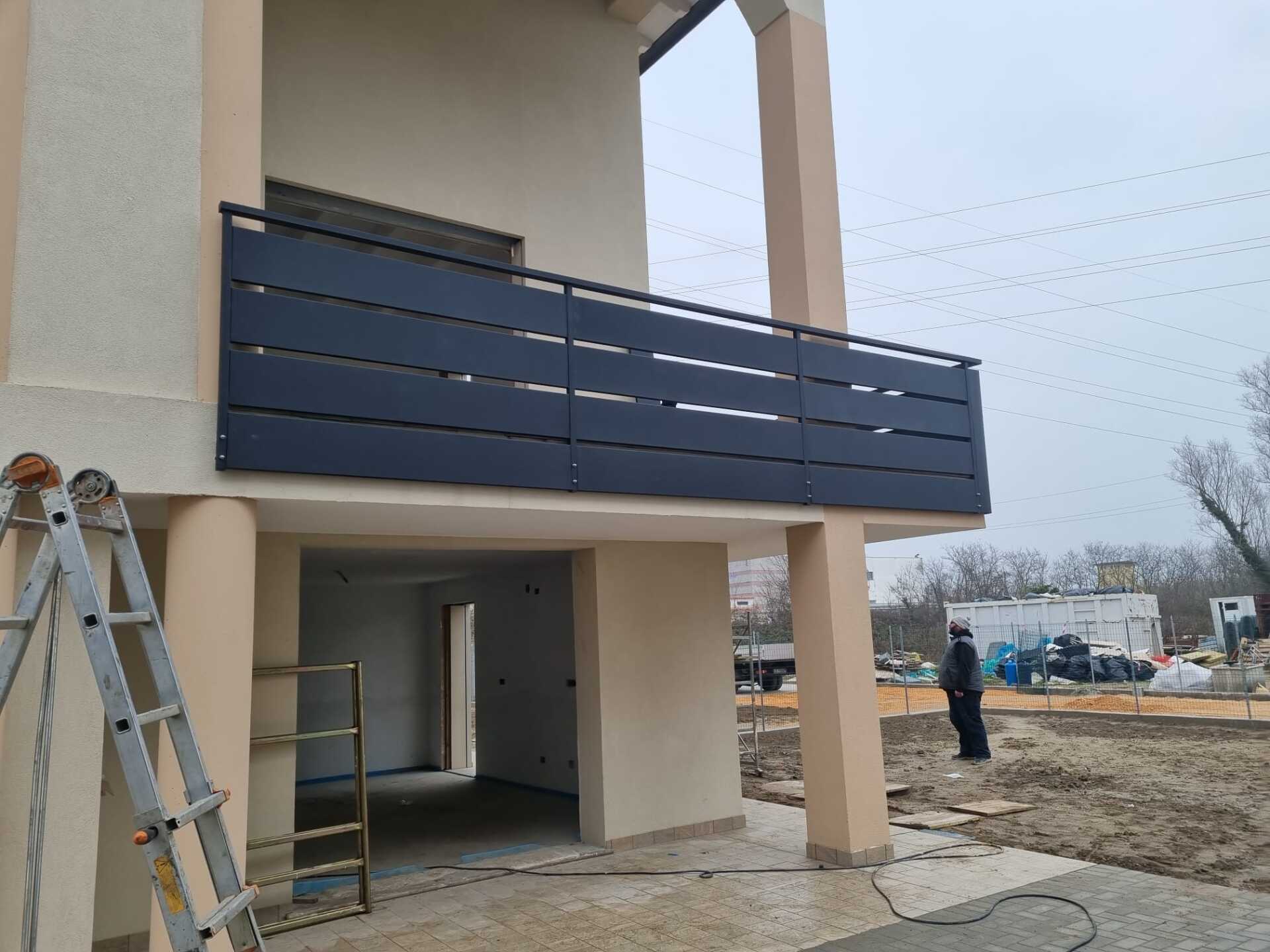 Ringhiera del balcone con listelli neri su una casa color cuoio con un garage parzialmente costruito al di sotto.