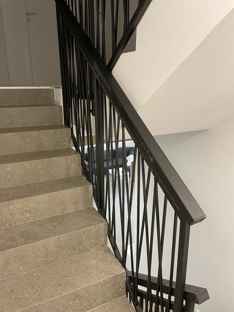 Scala in cemento con ringhiera in metallo nero in un edificio.