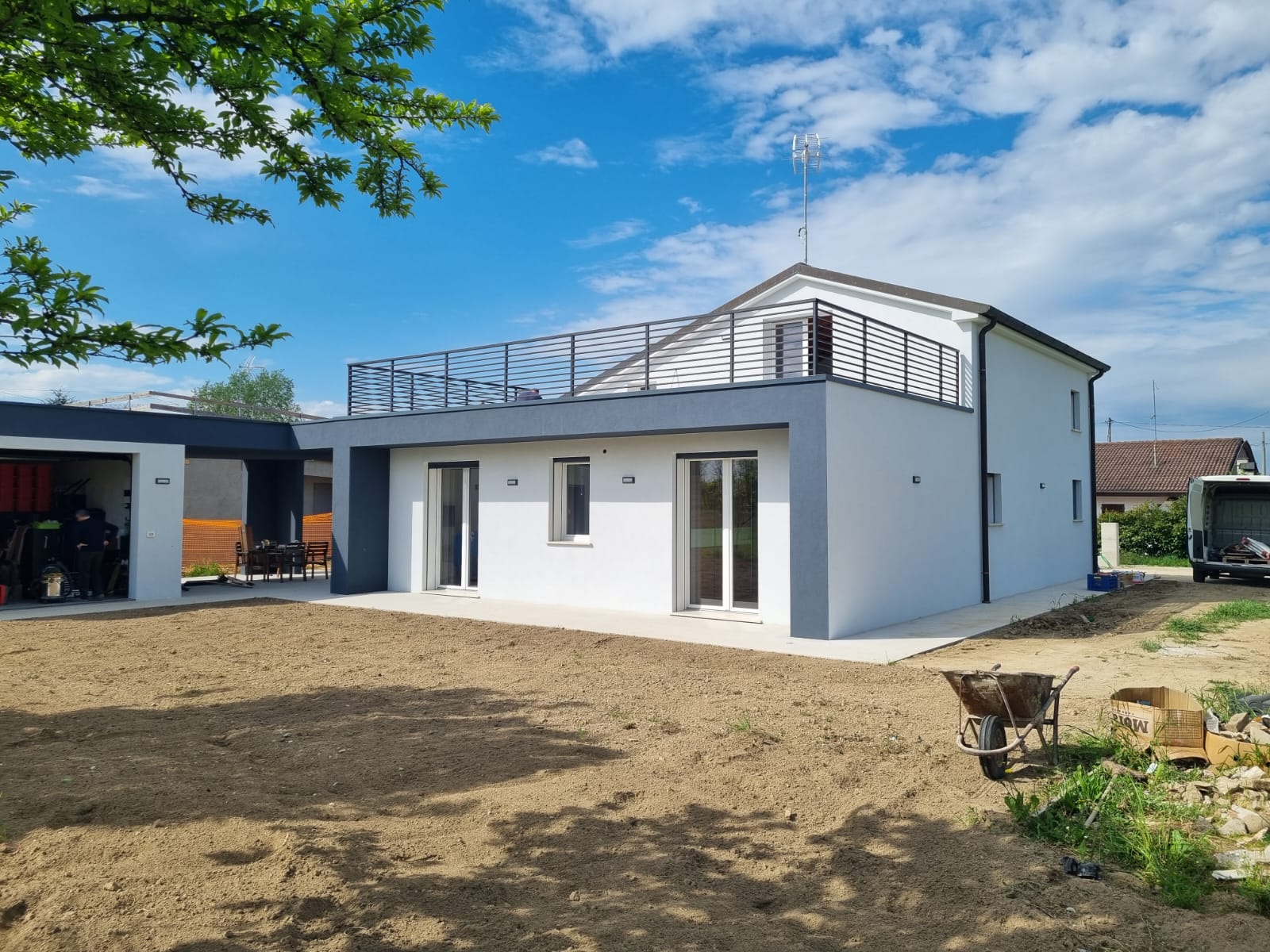 Moderna casa a due piani con balcone sul tetto piano e garage annesso in una giornata di sole.