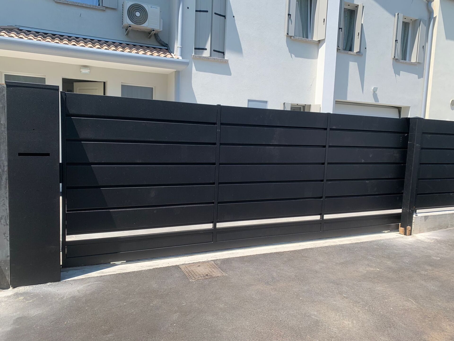 Cancello orizzontale nero di fronte a un edificio bianco.