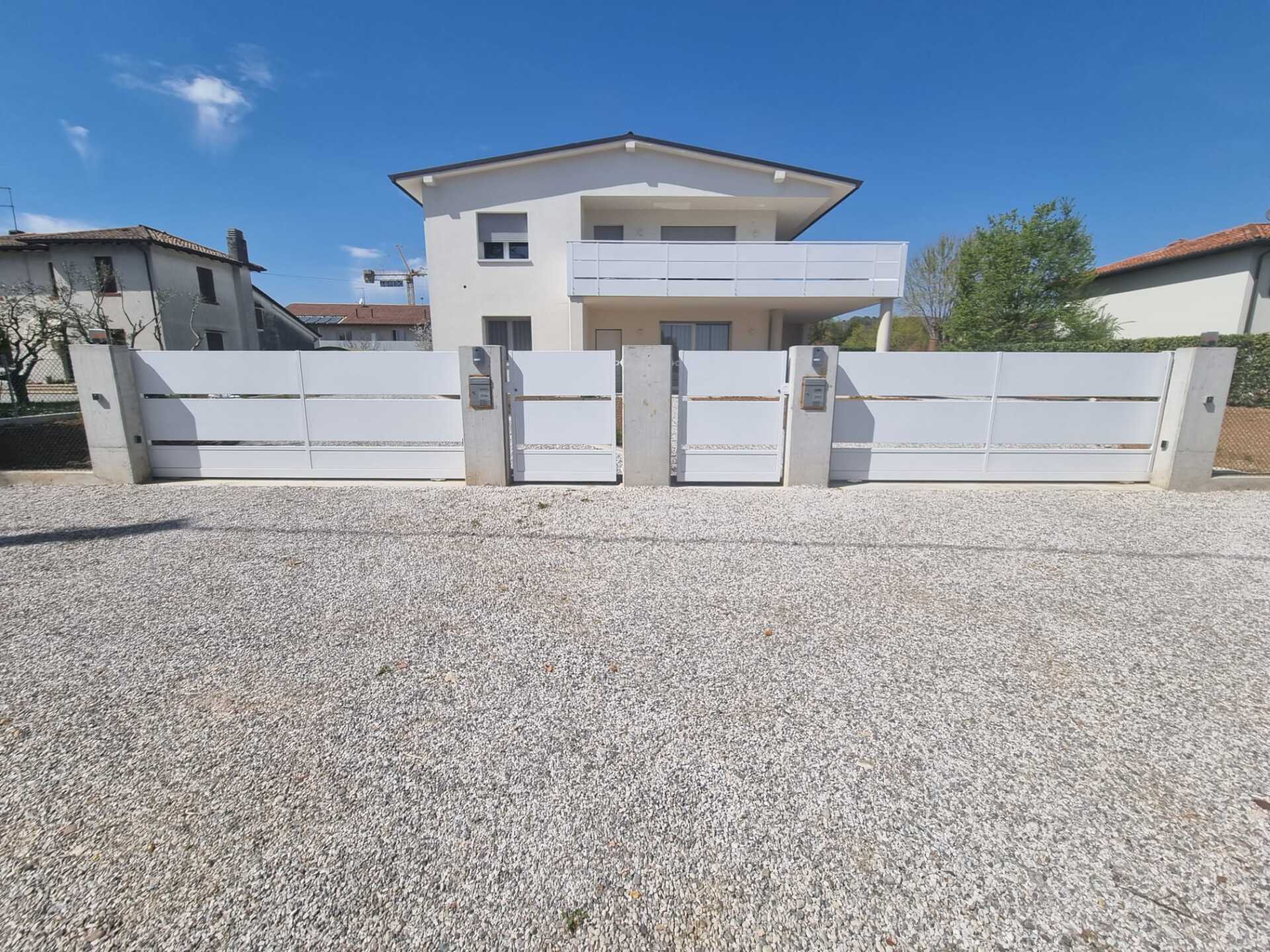 Casa bianca con recinzione bianca e vialetto di ghiaia.