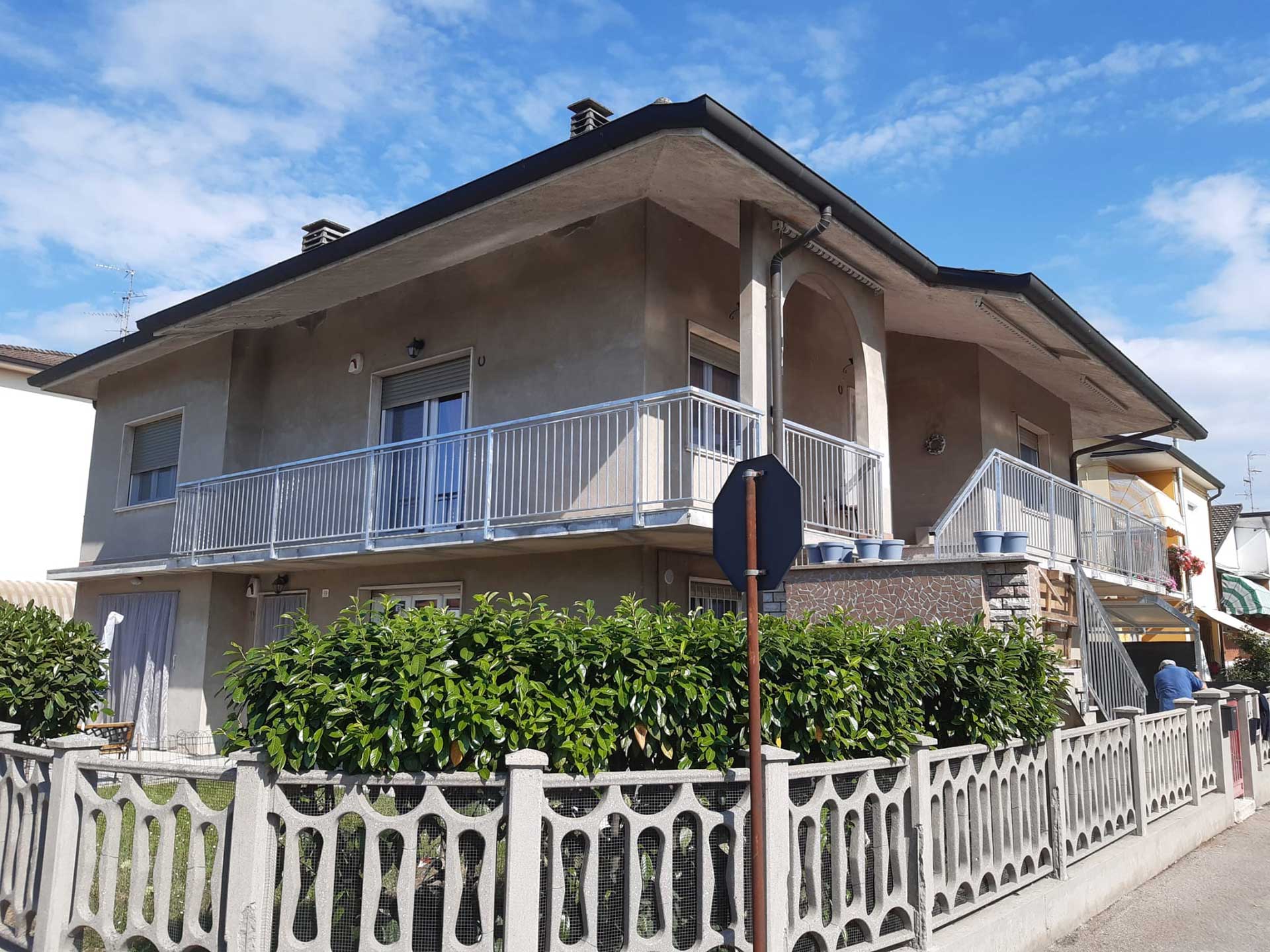 Edificio in stucco a due piani con balconi e una recinzione decorativa. Cielo coperto.