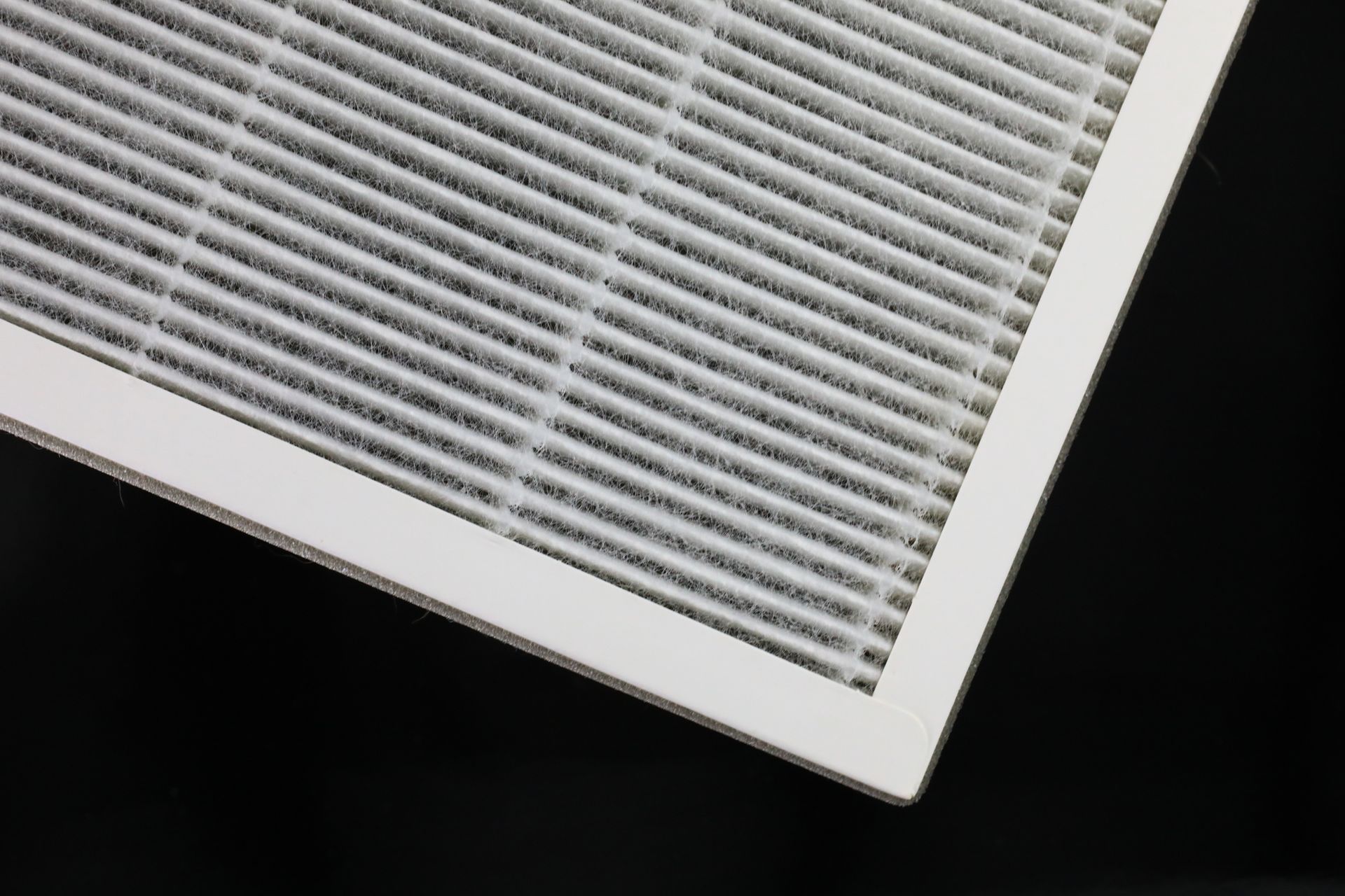 A close up of a white air filter on a black background.