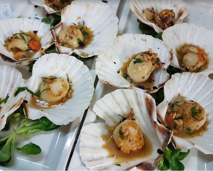 Un piatto bianco condito con pesce fritto, gamberi, calamari e fette di limone.