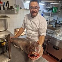 Un piatto di gamberetti cotti su un tavolo blu.