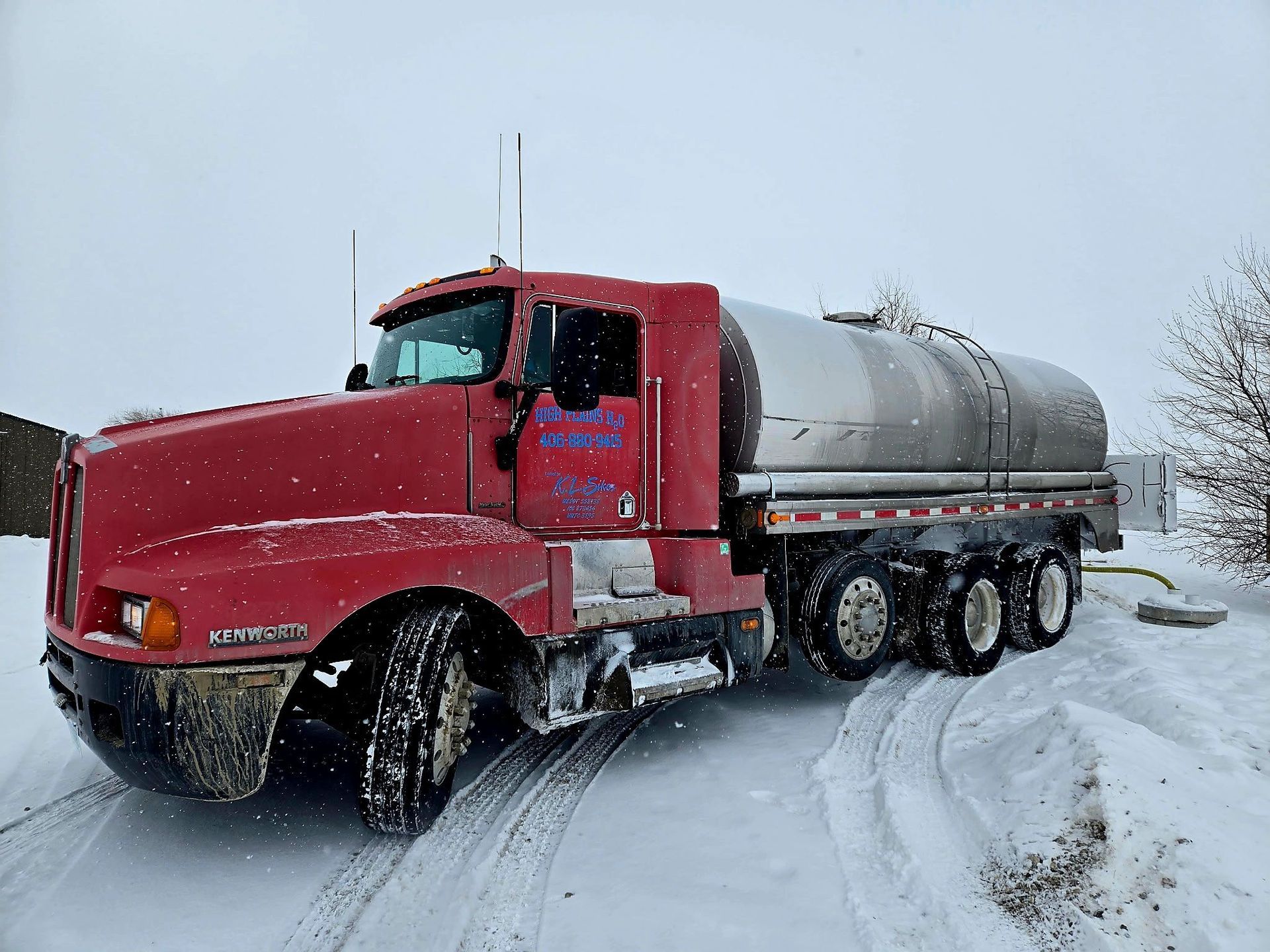 Red tanker truck in snowy conditions.