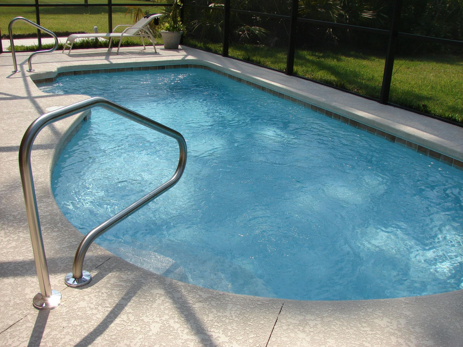 Small backyard swimming pool with a metal handrail.