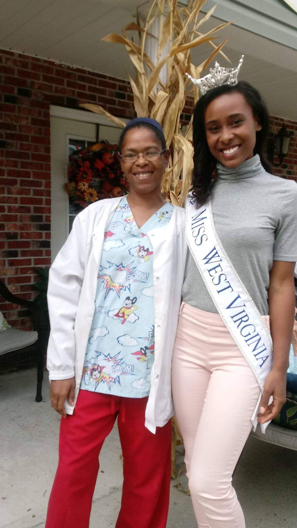 Two women pose outdoors: one in scrubs, the other wearing a Miss West Virginia sash and crown.