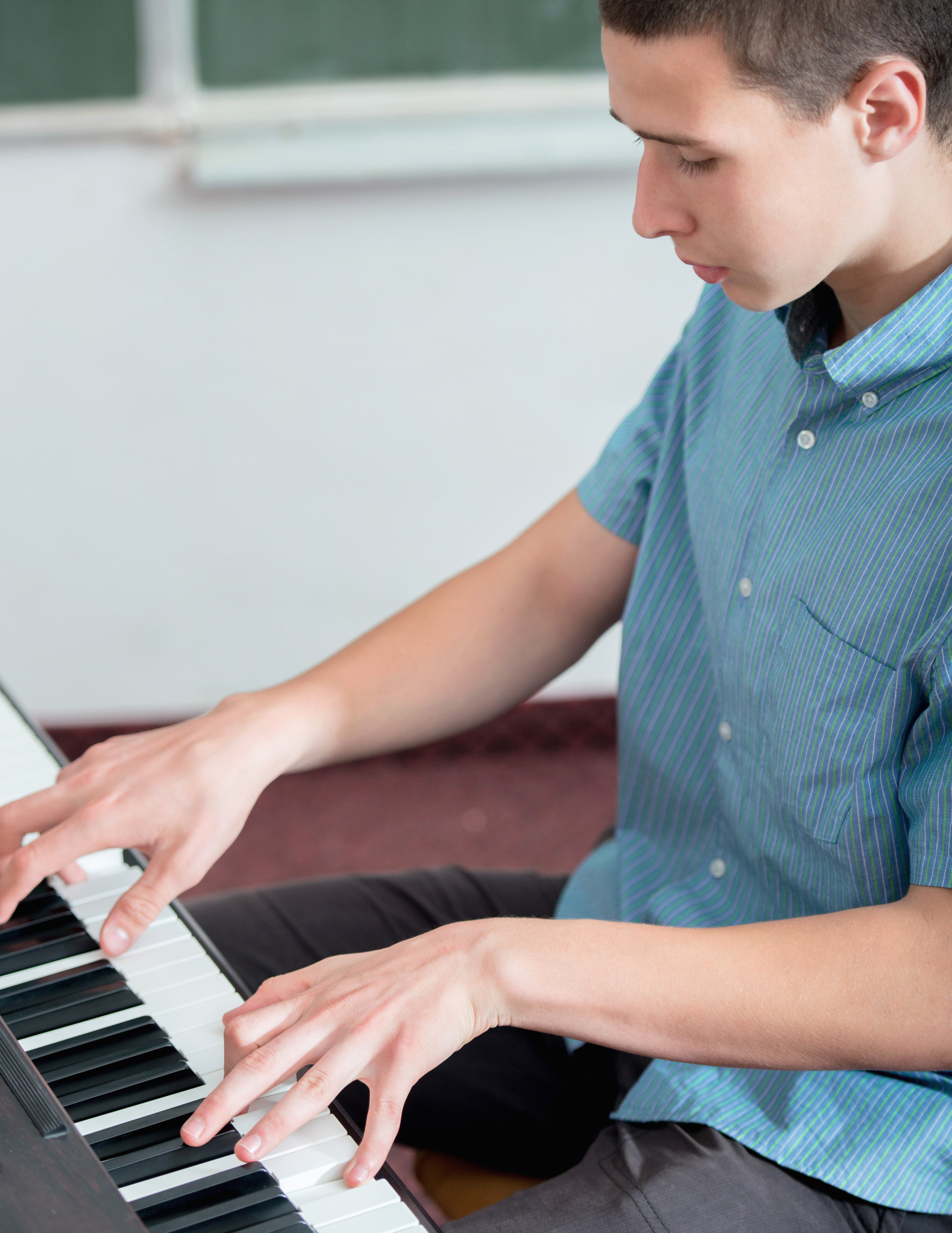 a young man in a blue shirt is playing a piano .