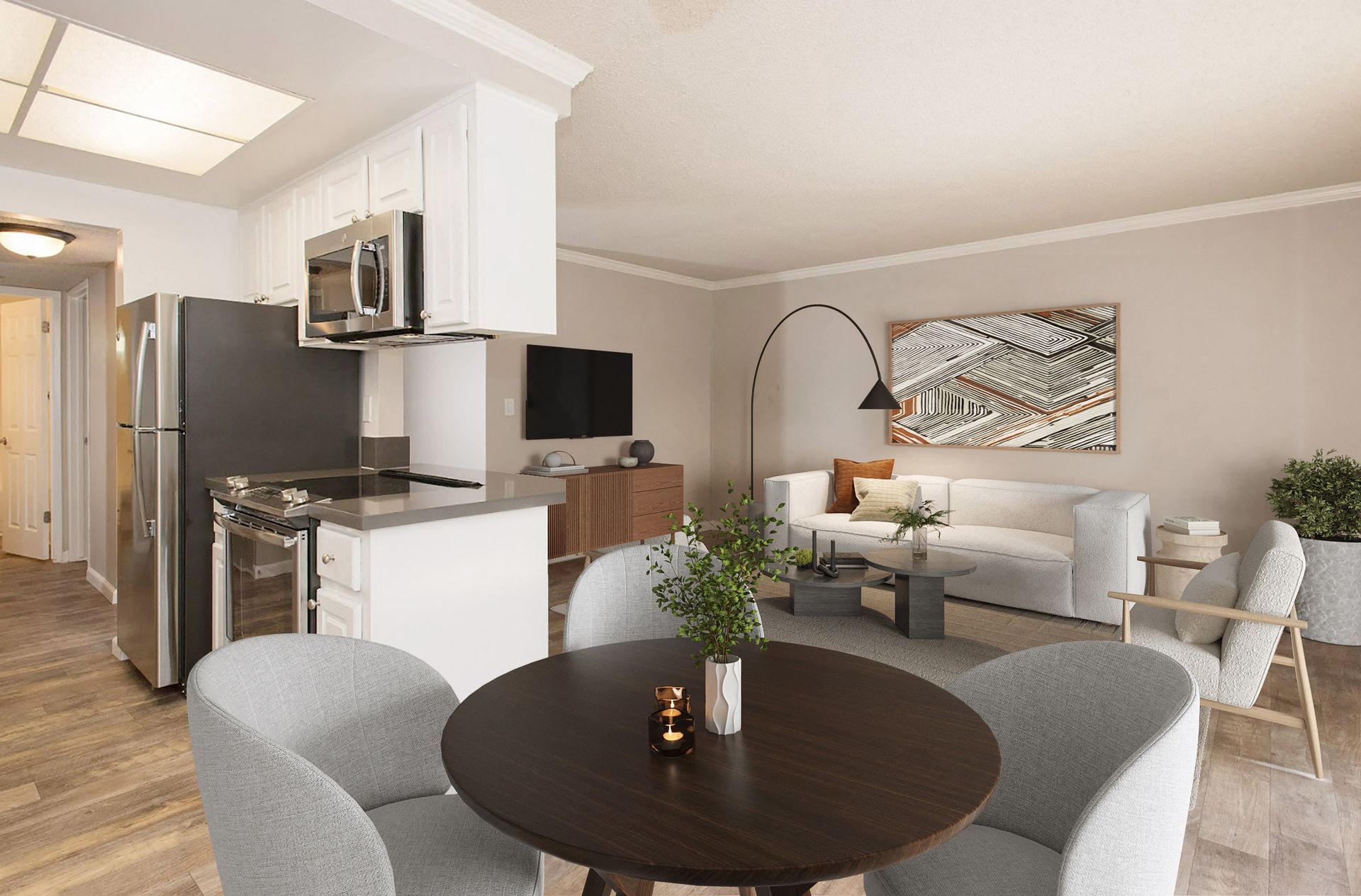 Open-concept living area with round dining table, gray chairs, and kitchen in the background.