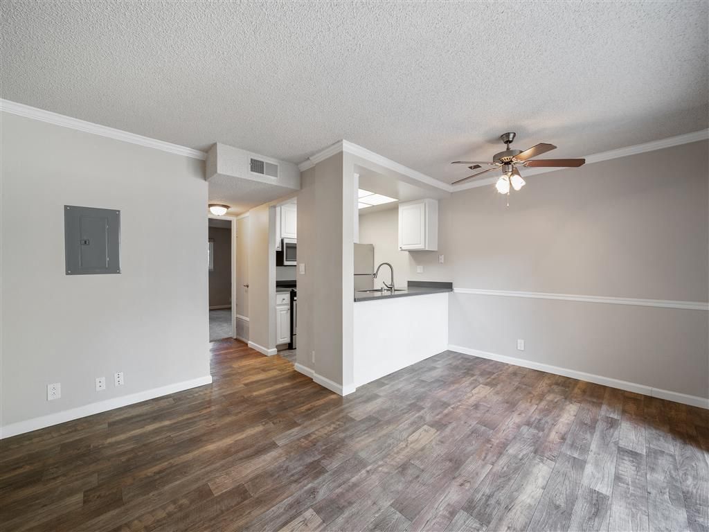 Open living area with kitchen pass-through, ceiling fan, and wood-look flooring.