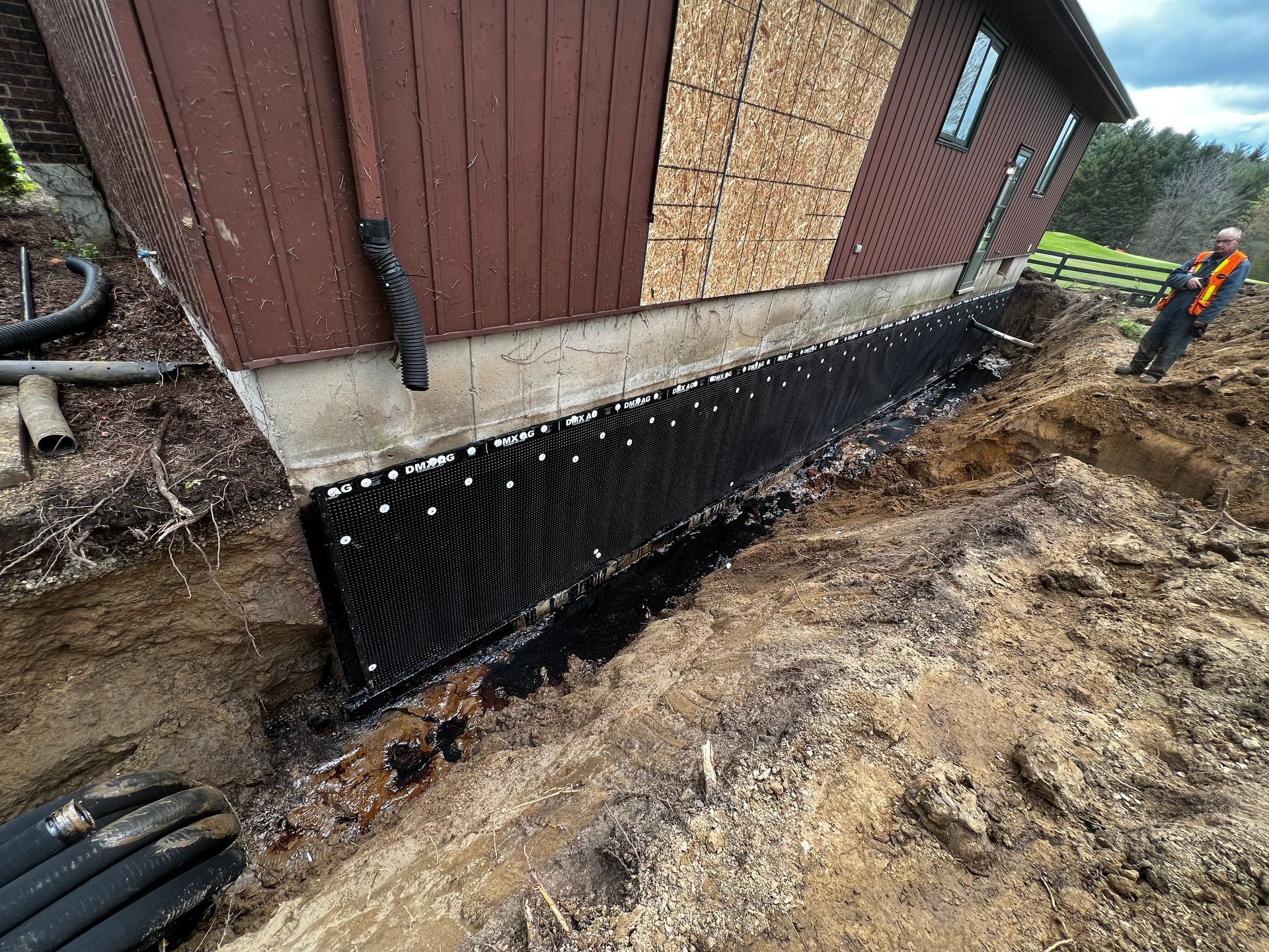 A man in an orange vest is inspecting the quality workmanship of the DMX waterproof membrane.