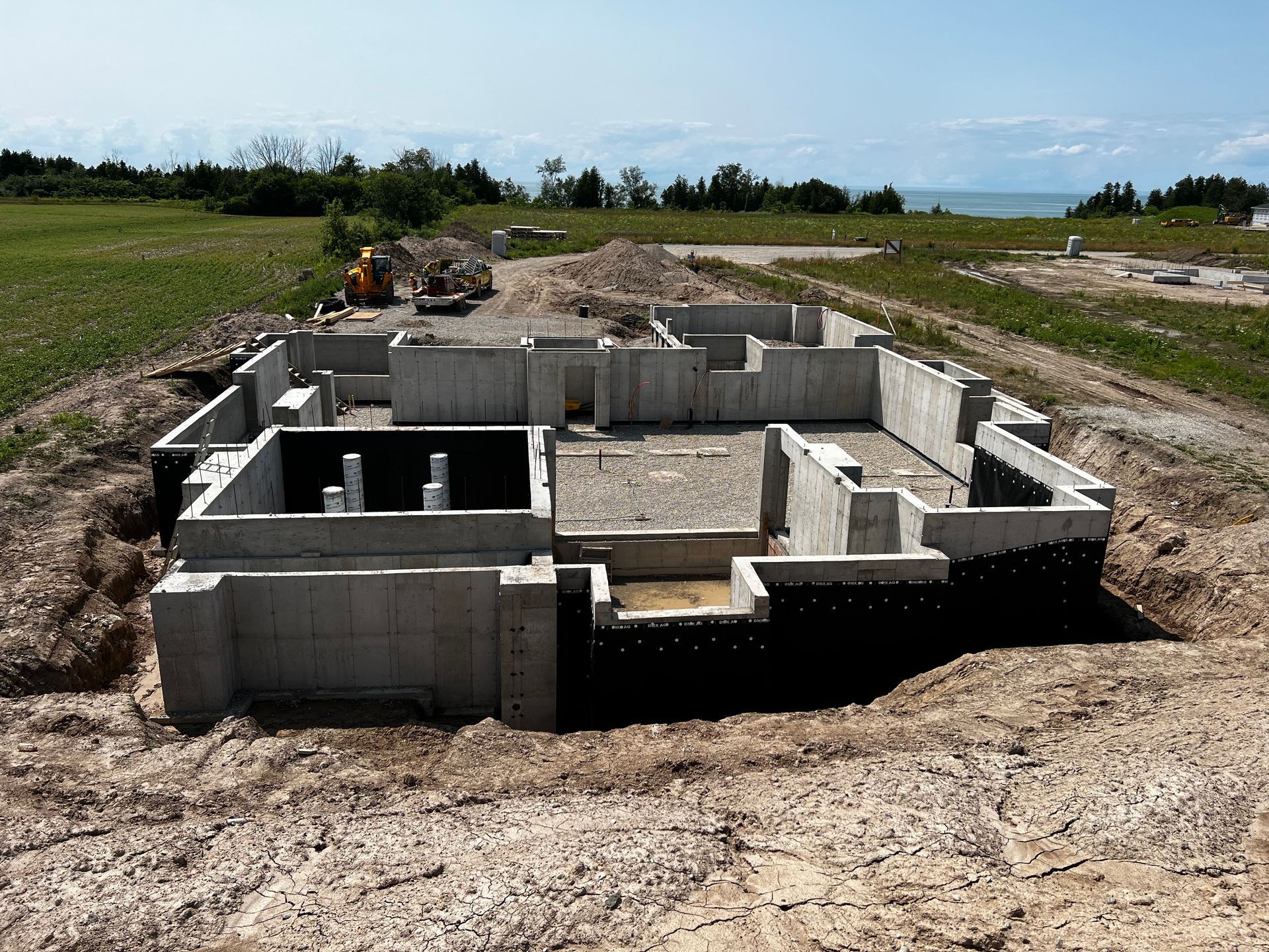 A completed traditional concrete foundation where JD Waterproofing has finished half of the waterproof membrane installation.