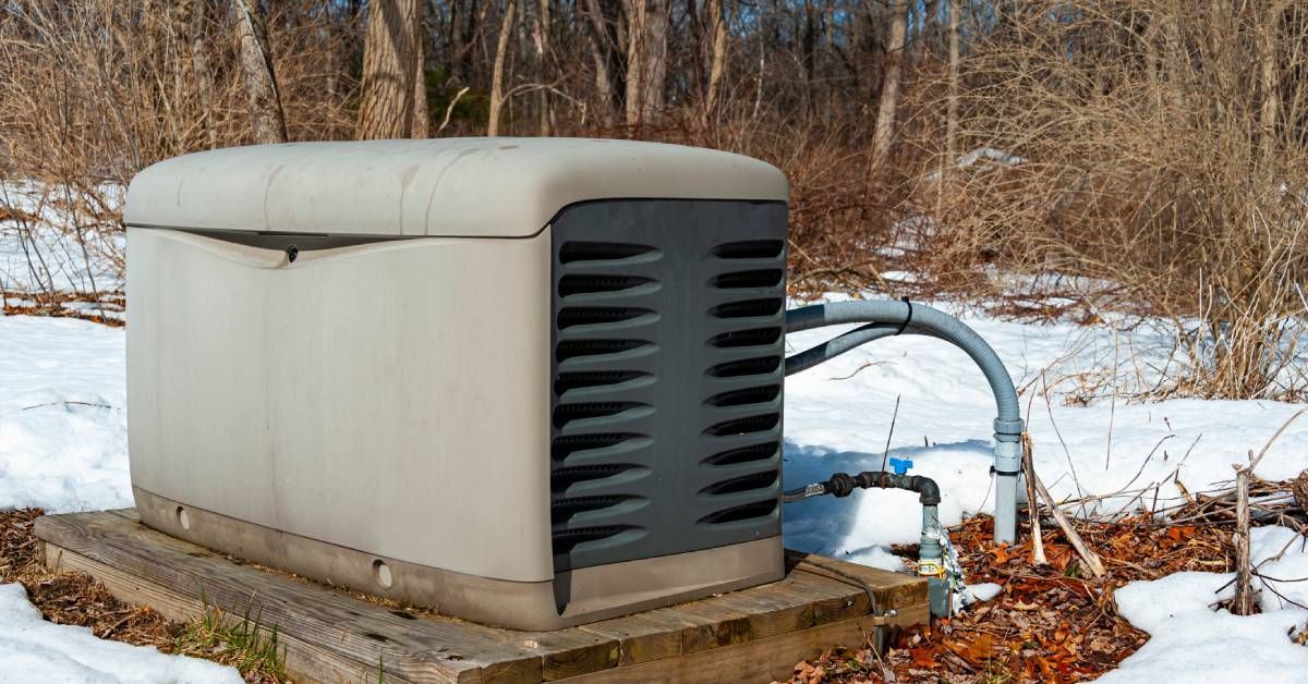  A residential standby generator on a wood platform with snow covering the ground around it.