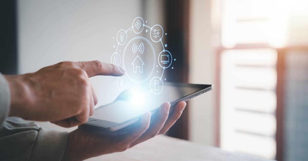 A man holds a tablet linked to a smart home network. A graphic of connected devices hovers above.