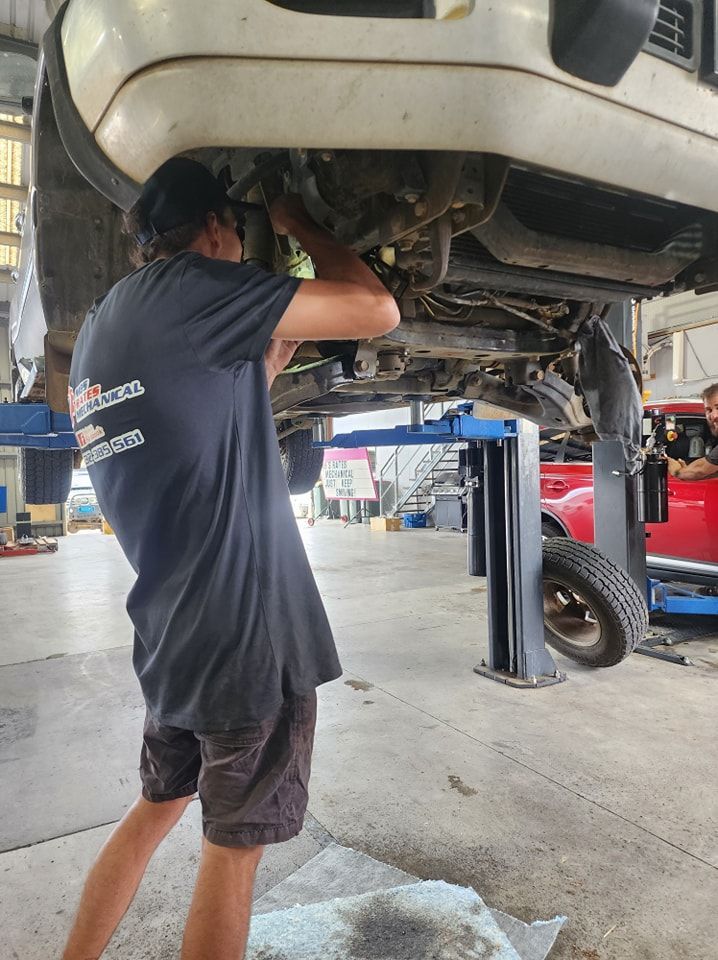 A Man Is Working On The Underside Of A Car In A Garage — M8S Rates Mechanical In Gladstone Central, QLD