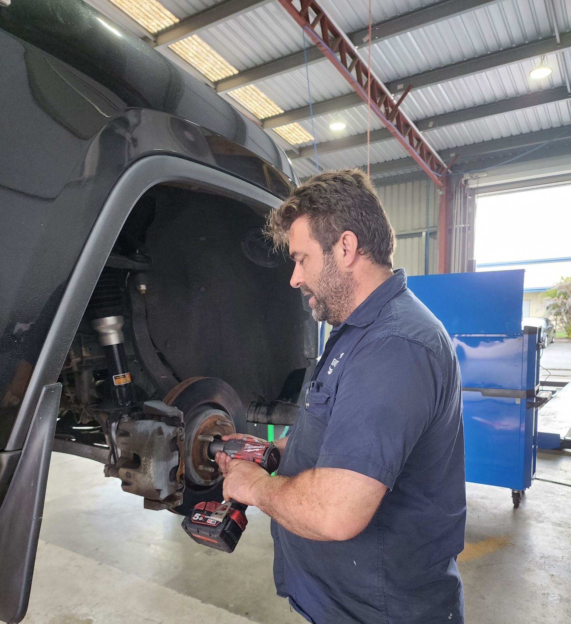 A Man Is Working On A Car In A Garage — M8S Rates Mechanical In Gladstone Central, QLD