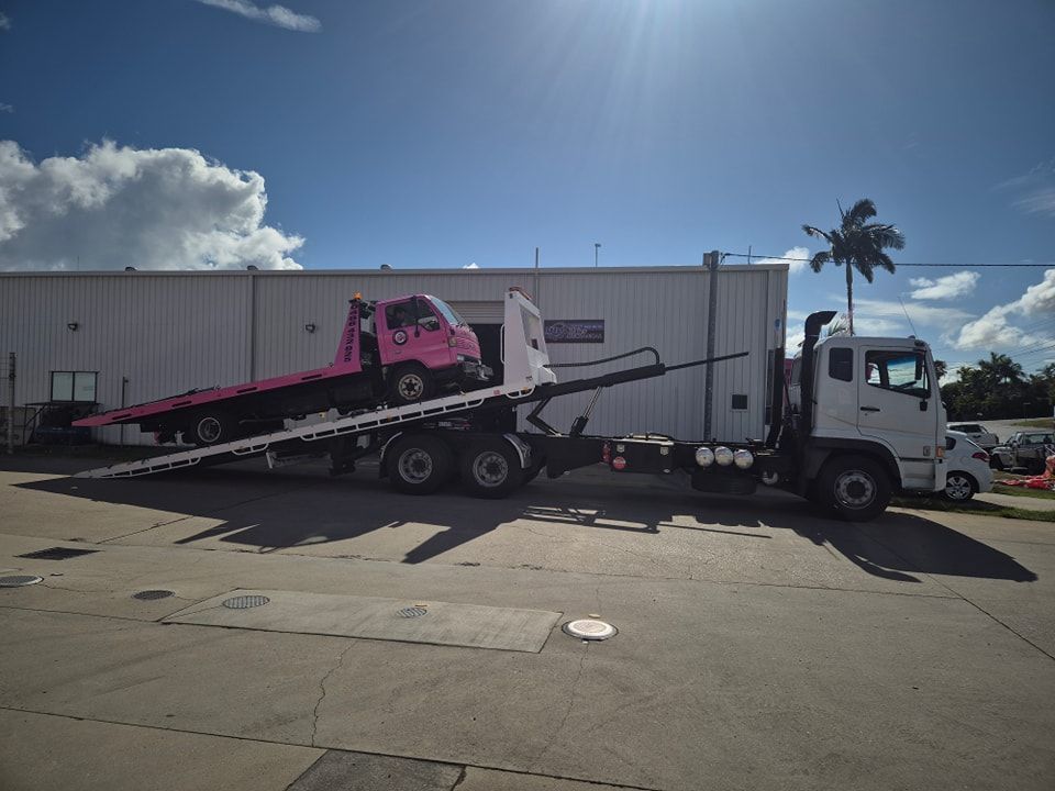 A Pink Tow Truck Is Being Towed By A White Truck — M8S Rates Mechanical In Gladstone Central, QLD