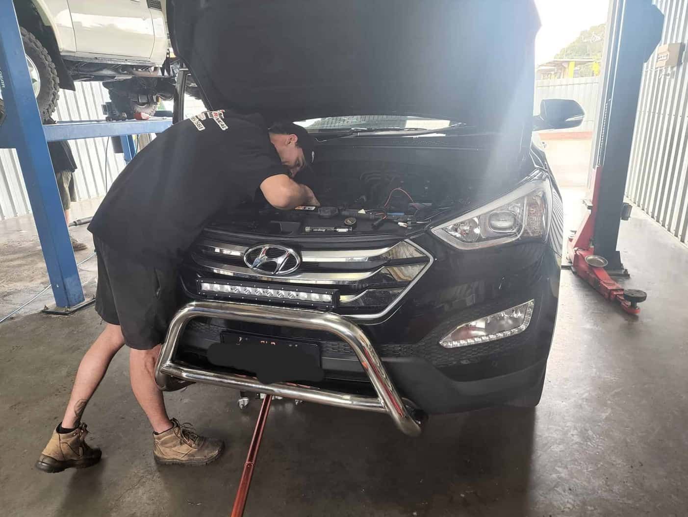A Man Is Working On The Hood Of A Car In A Garage — M8S Rates Mechanical In Gladstone Central, QLD