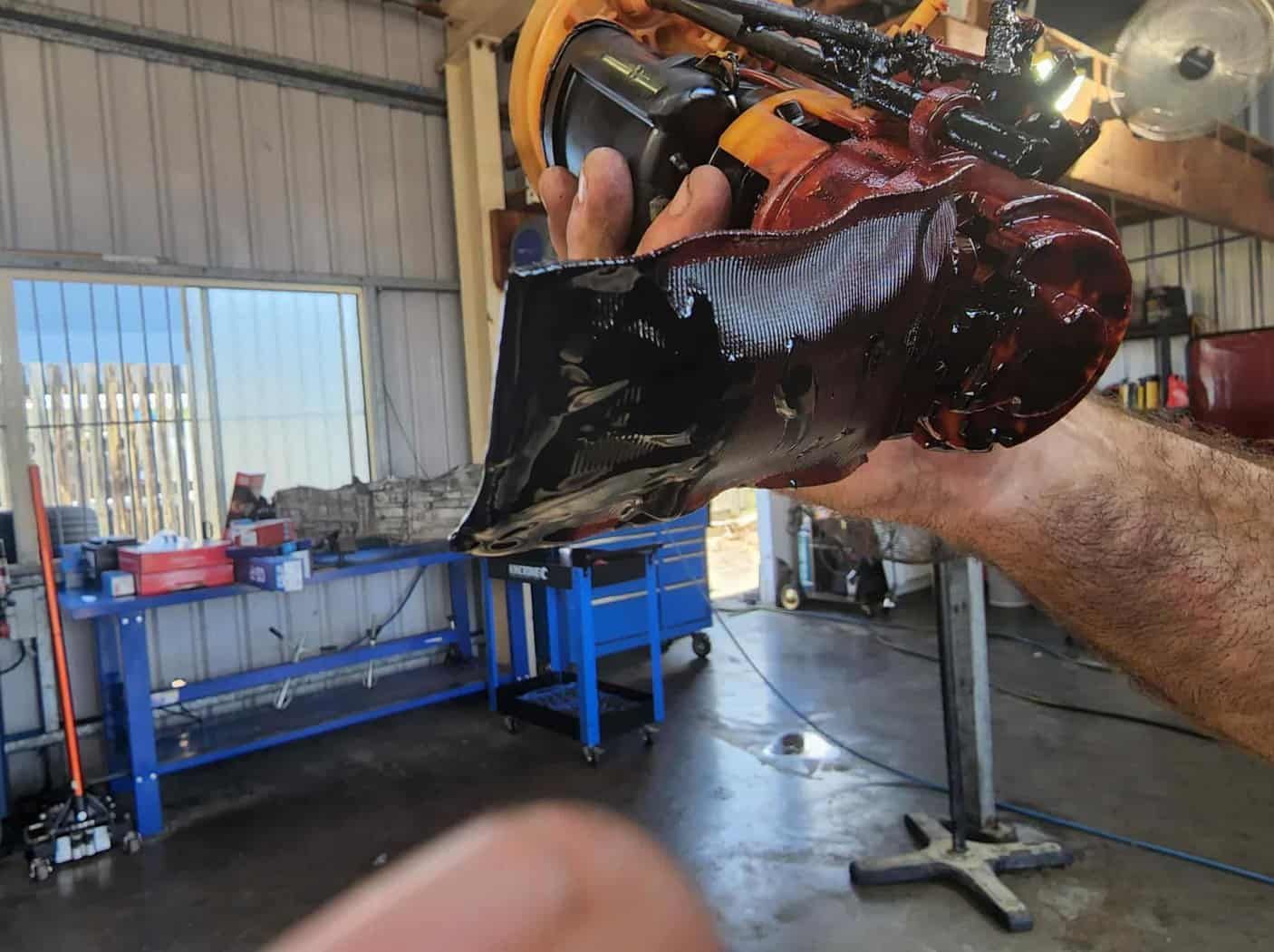 A Person Is Holding A Piece Of Metal In Their Hand In A Garage — M8S Rates Mechanical In Gladstone Central, QLD