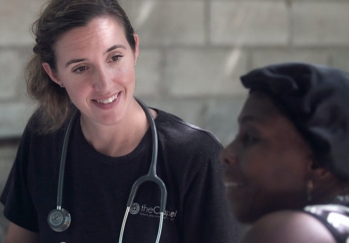 A woman with a stethoscope around her neck is talking to a patient