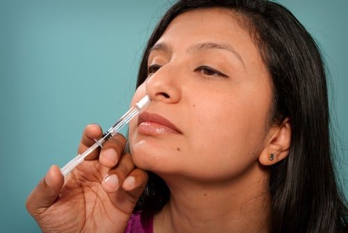 A woman is getting an injection in her nose.