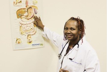 A doctor is pointing at a diagram of the human digestive system.