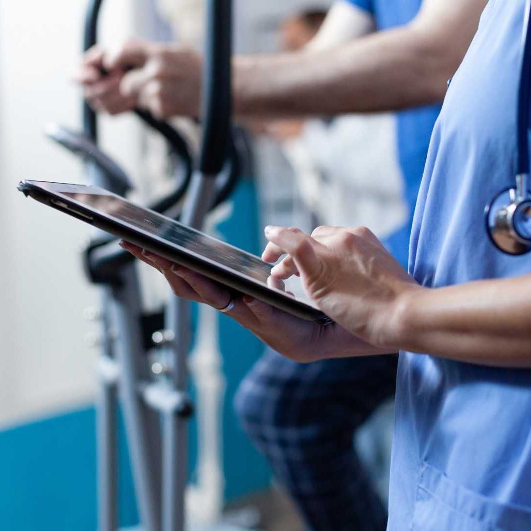 A nurse with a stethoscope around her neck is using a tablet