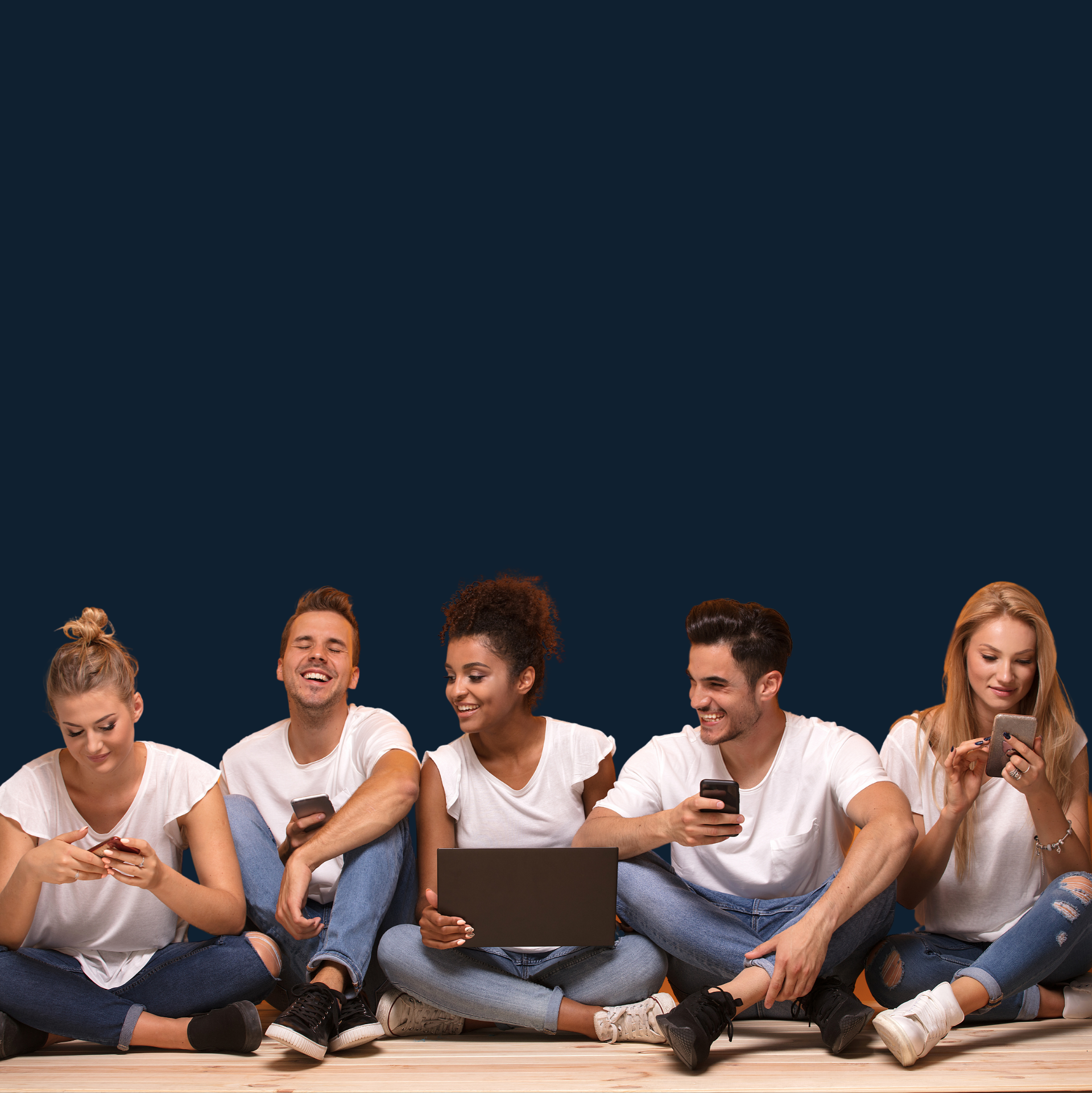Five people sitting on the floor using phones and laptop against a salmon-colored backdrop.