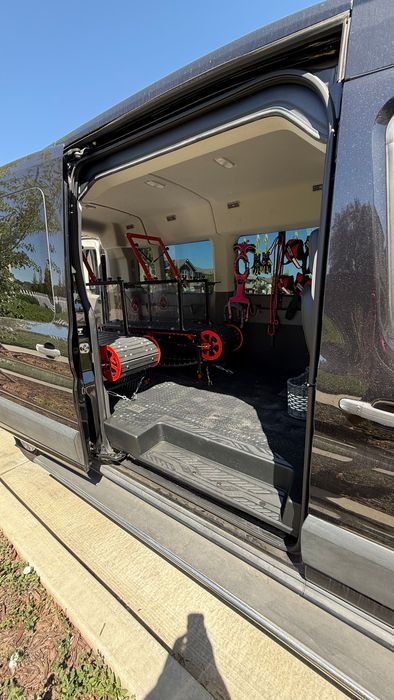 The back of a van with the door open and a bicycle in the back.