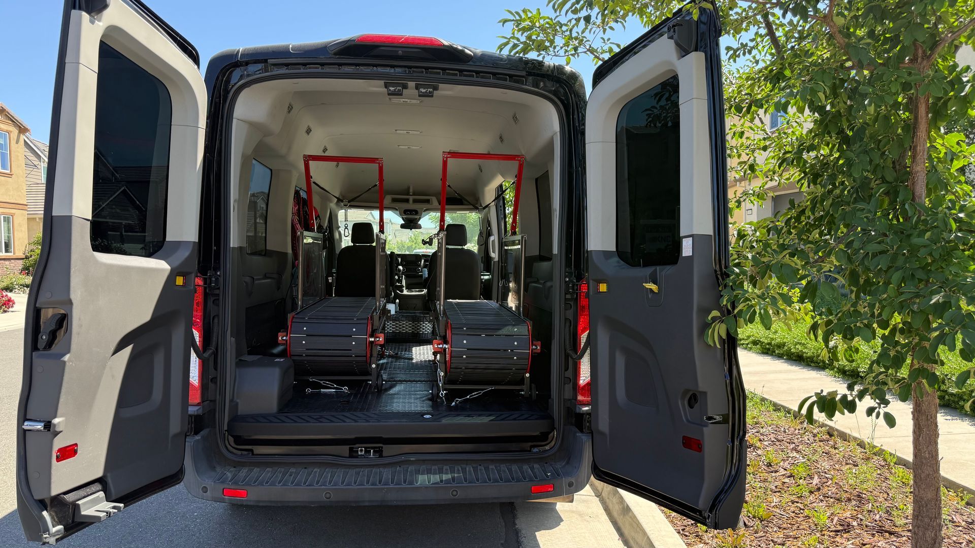 The back of a van with its doors open is parked on the side of the road.