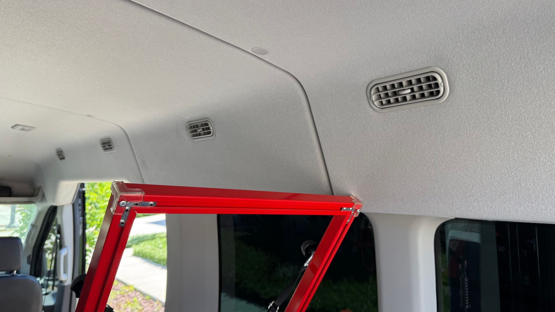 A red ladder is hanging from the ceiling of a van.