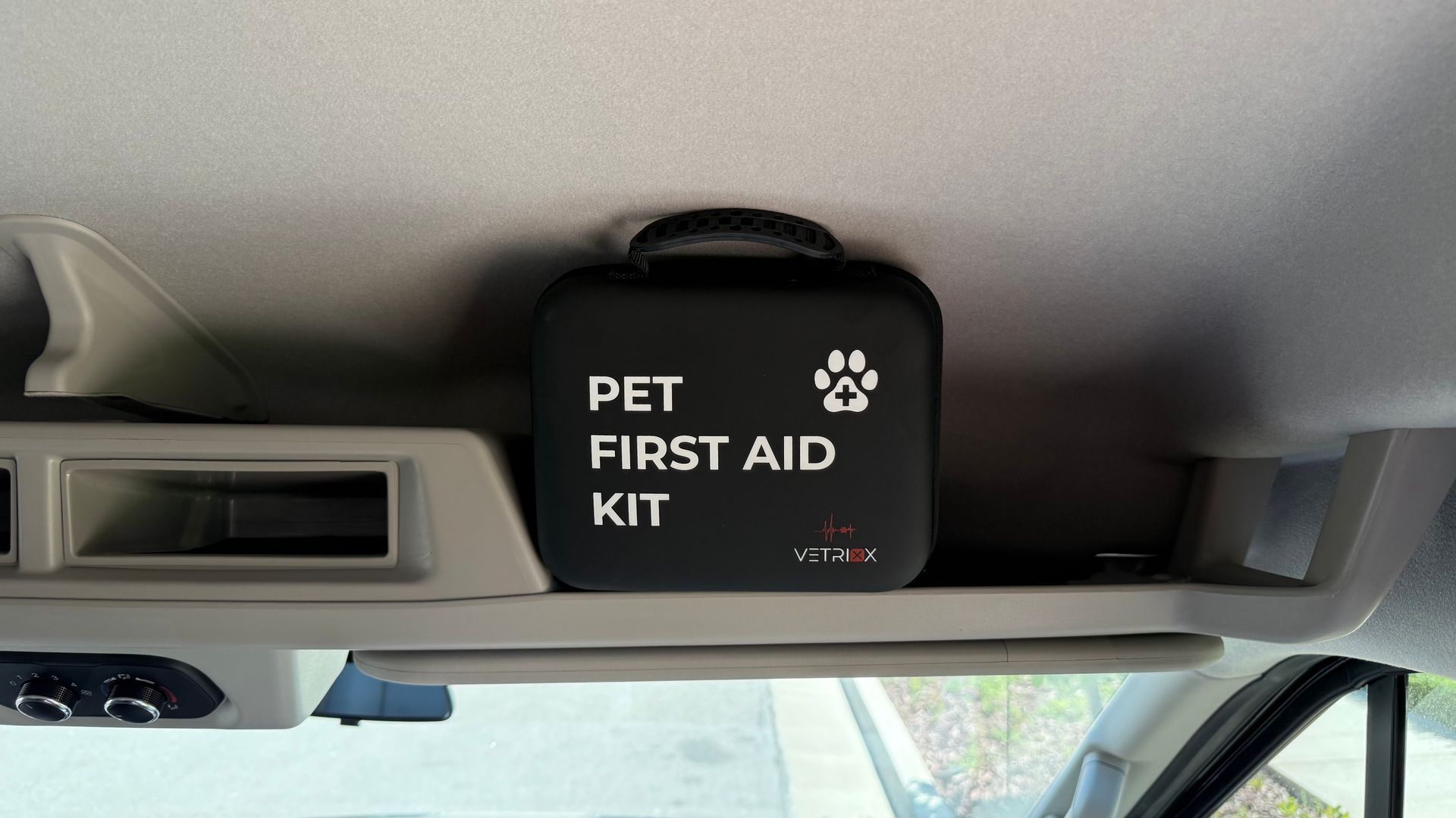 A pet first aid kit is hanging from the ceiling of a car