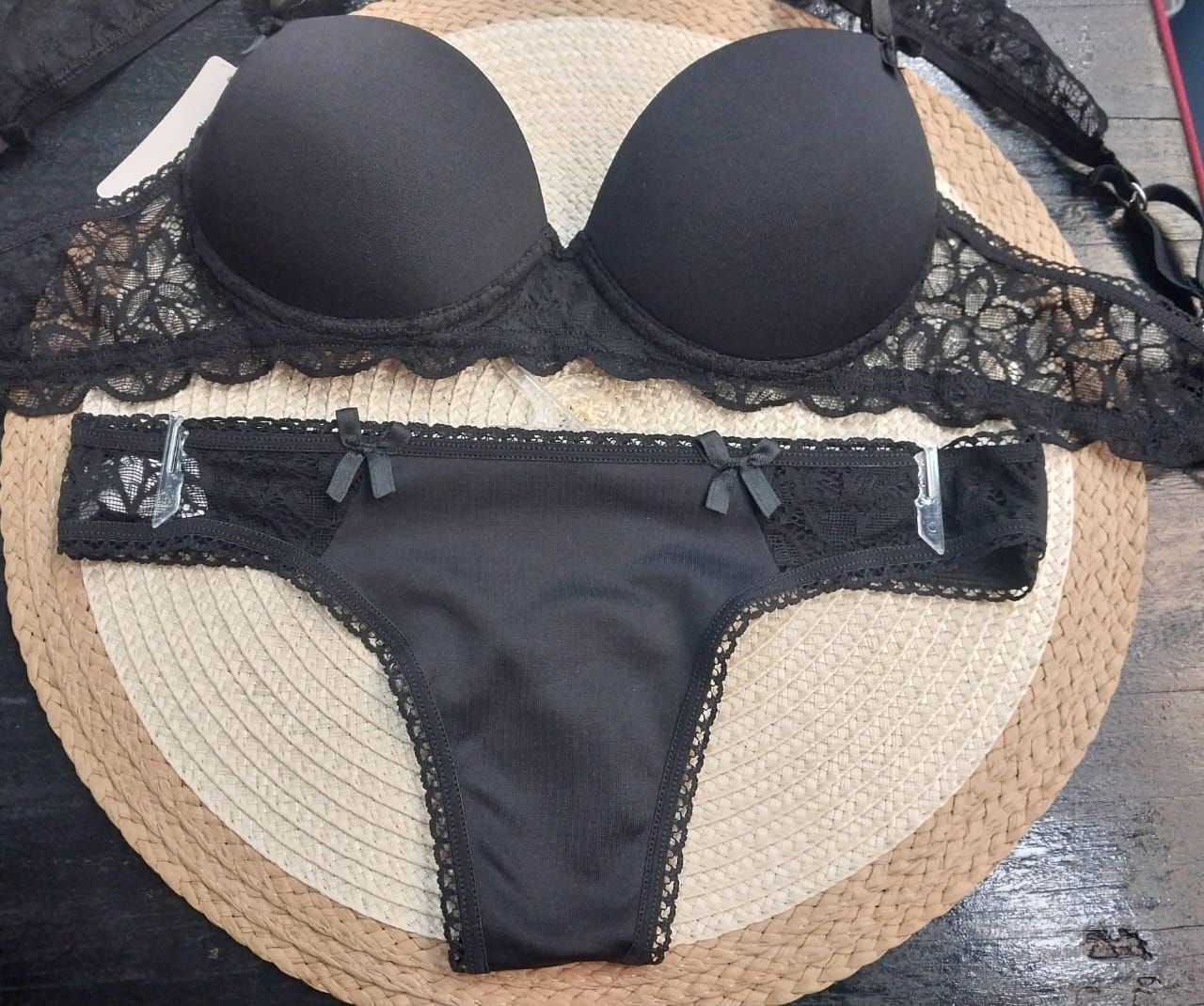 Conjunto de lencería negra con sujetador y braguita sobre esterilla tejida.