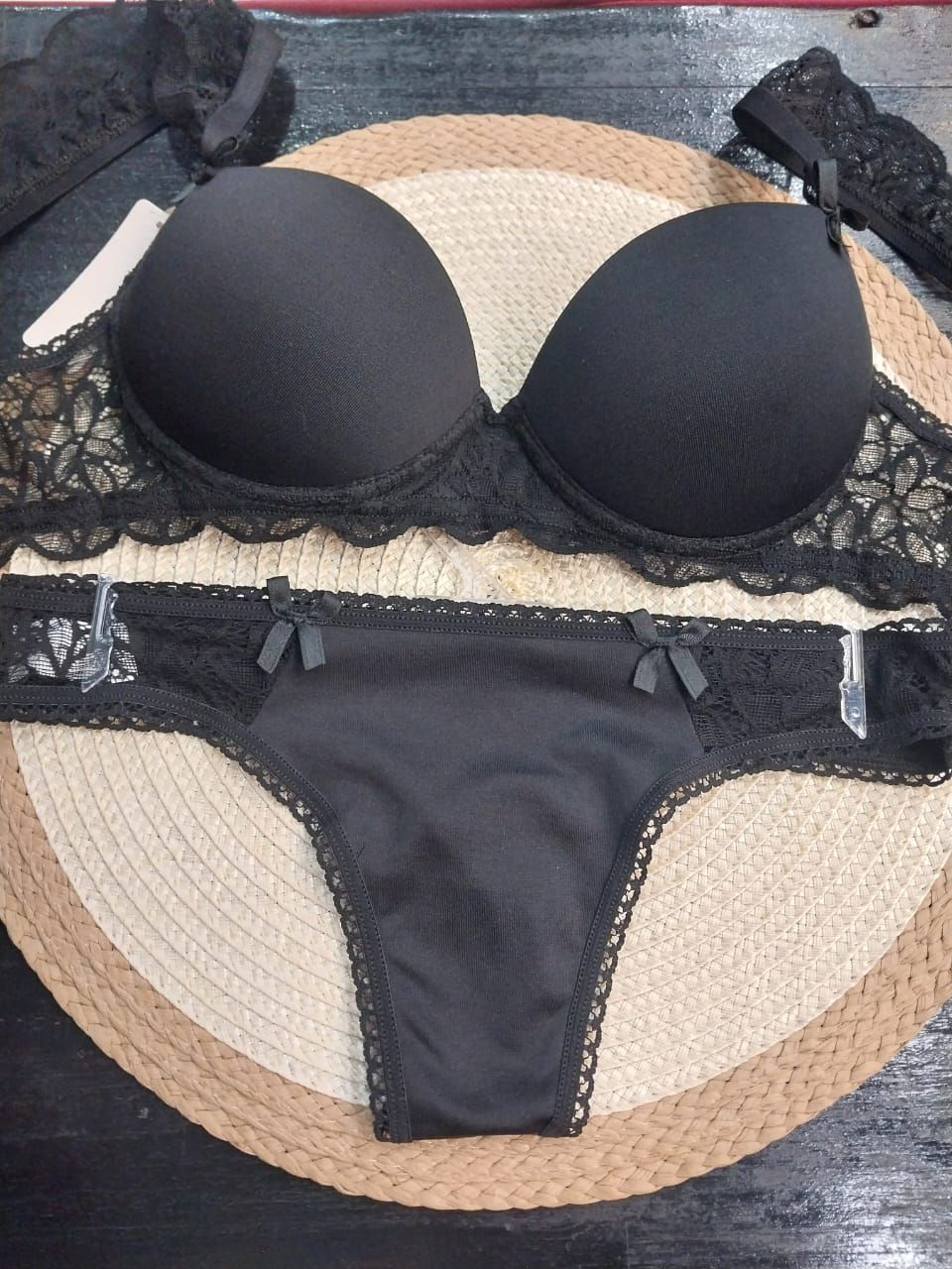 Conjunto de lencería negra con sujetador y braguita sobre esterilla tejida.