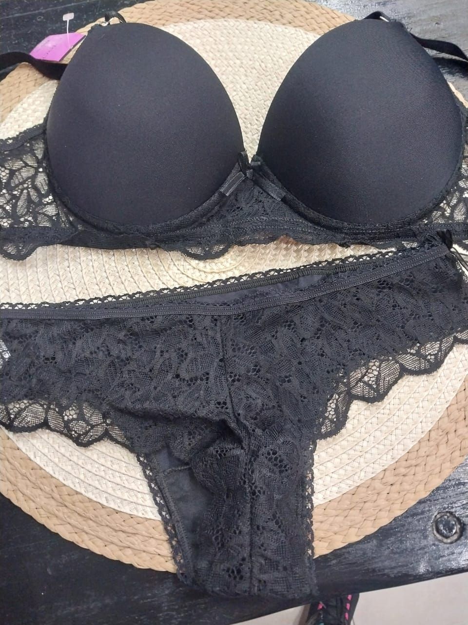Conjunto de lencería negra: sujetador y braguita a juego con ribete de encaje sobre tapete tejido.