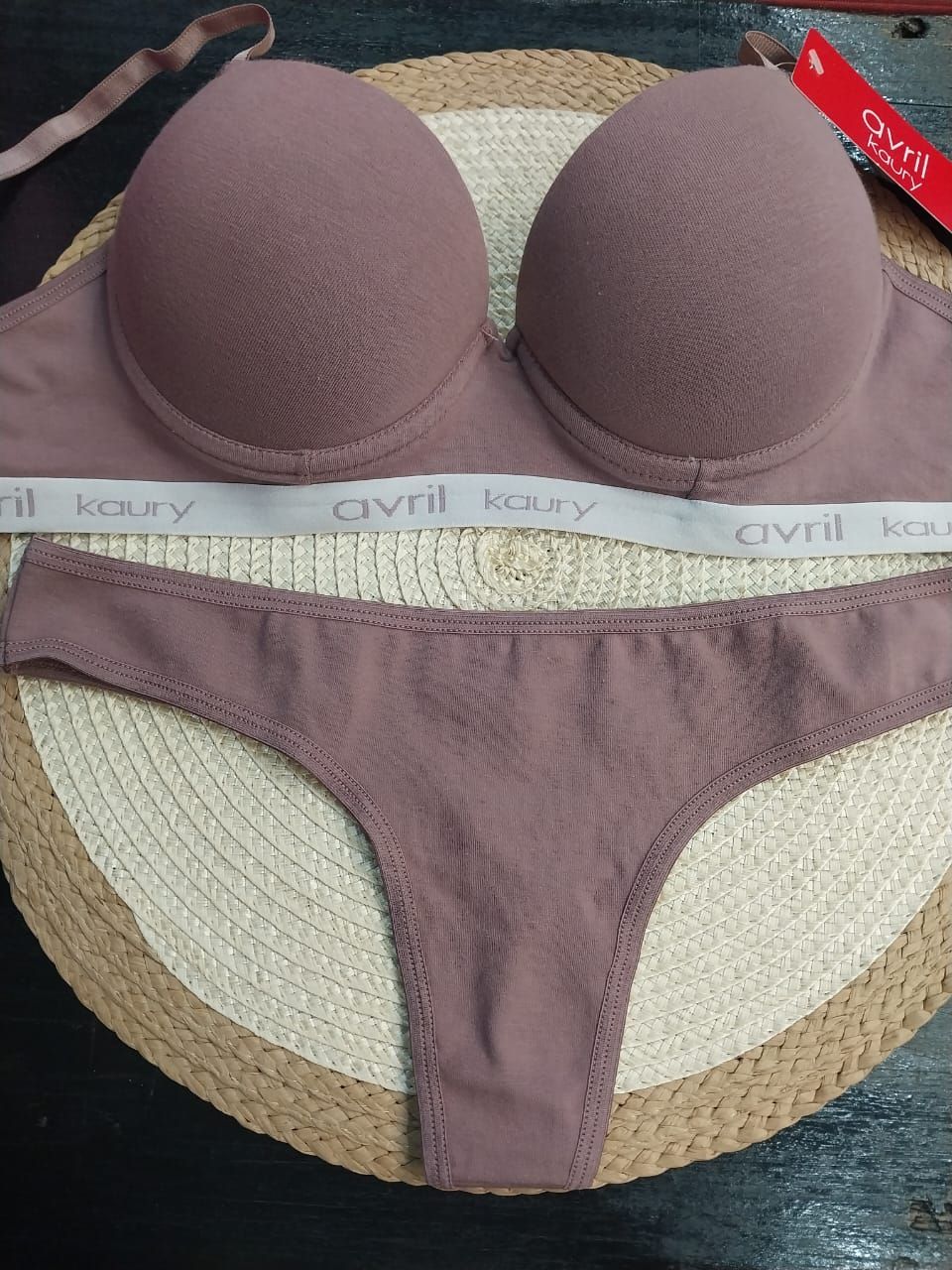 Sujetador malva y tanga a juego sobre tapete tejido.