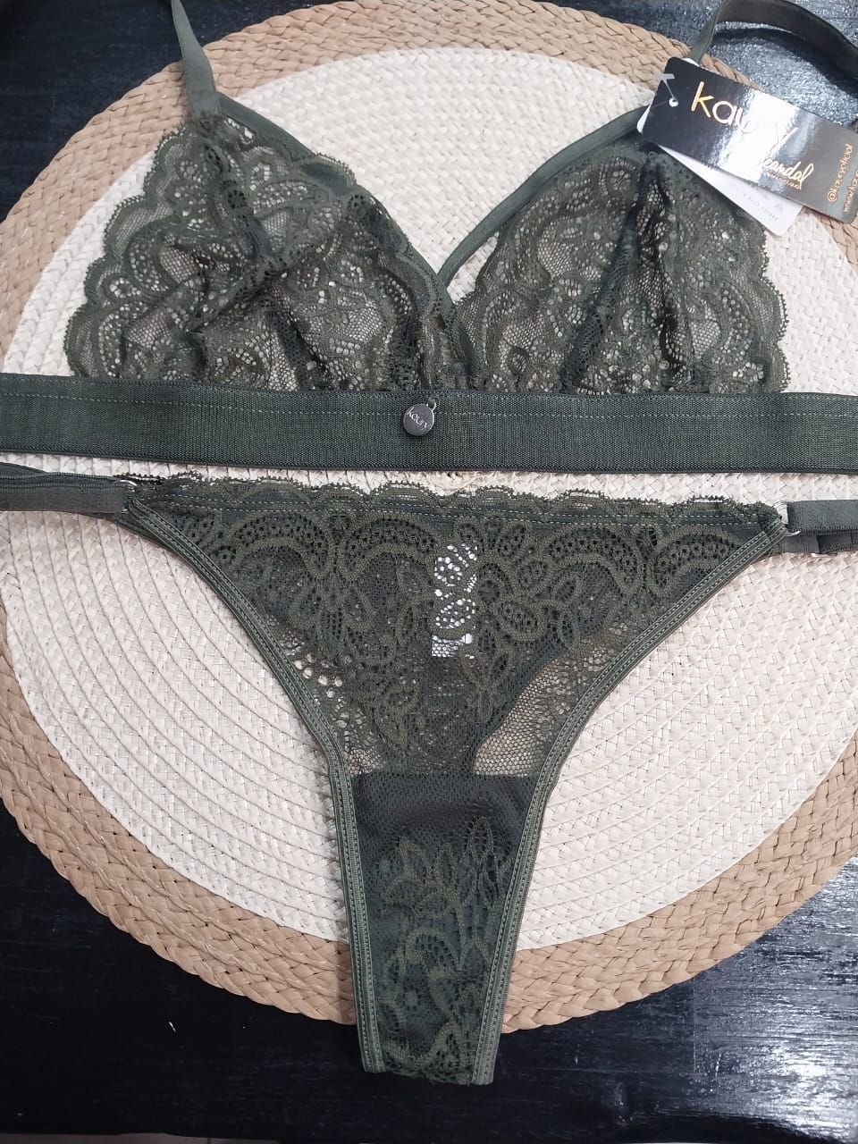 Conjunto de lencería de encaje verde sobre tapete tejido redondo.